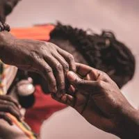 Close view of two people holding hands gently, showing support, care, and connection