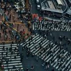 Top-down view of a crowded urban crosswalk with many people walking across multiple zebra crossings