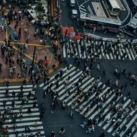 Top-down view of a crowded urban crosswalk with many people walking across multiple zebra crossings