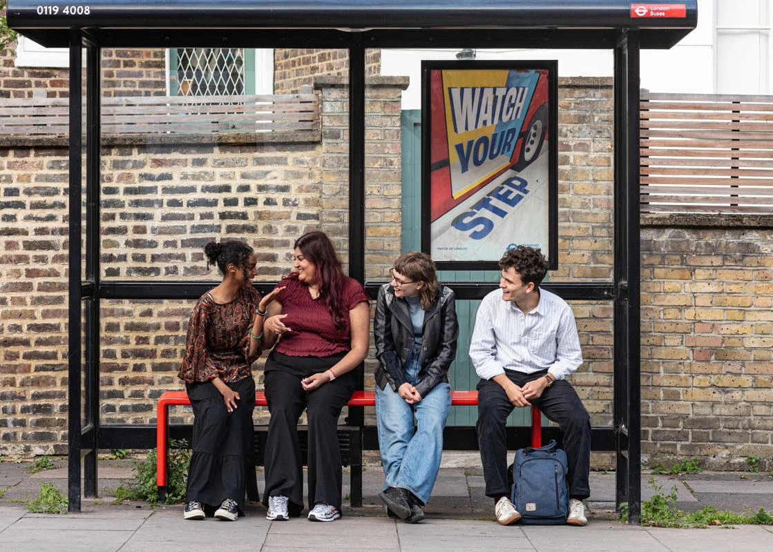 Image shows people chatting at a bus stop