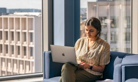 A propective student looking at a laptop with LSE campus in the background