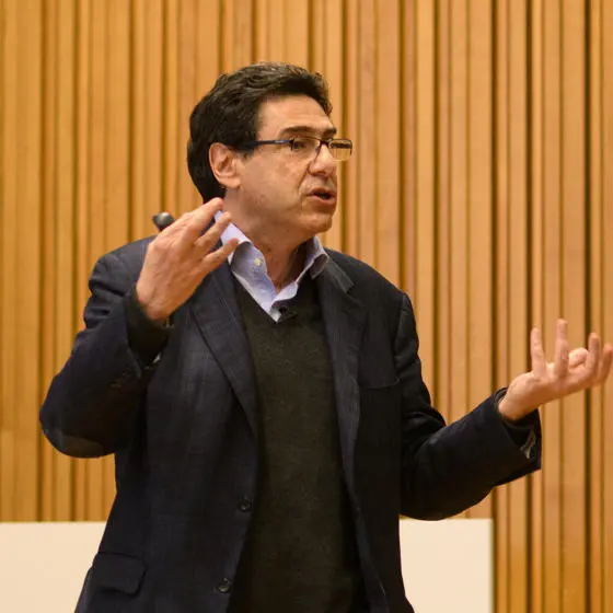 Philippe Aghion stands giving a talk. Behind him is a wood panelled wall.