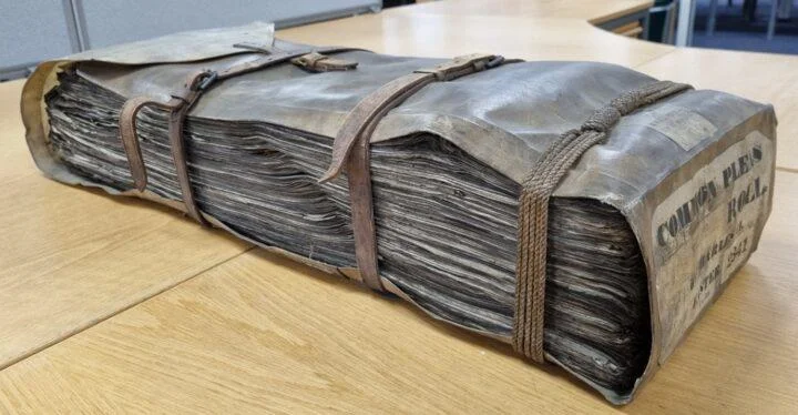 Historic bound archive volume containing preserved legal or administrative records, bound with leather straps and rope, wrapped in a protective cover.