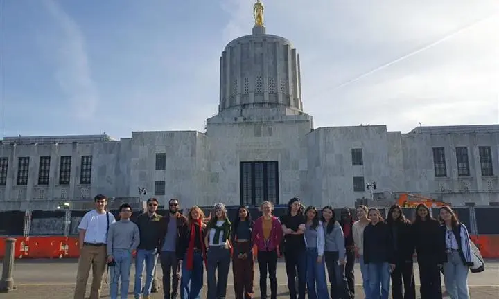 A building with a group of students standing in a line in front of it.