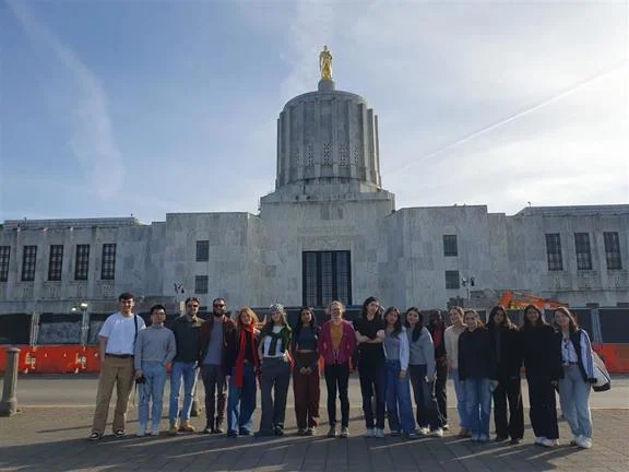 A building with a group of students standing in a line in front of it.