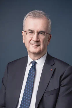 Portrait of François Villeroy de Galhau wearing a dark suit, against a plain dark blue background.