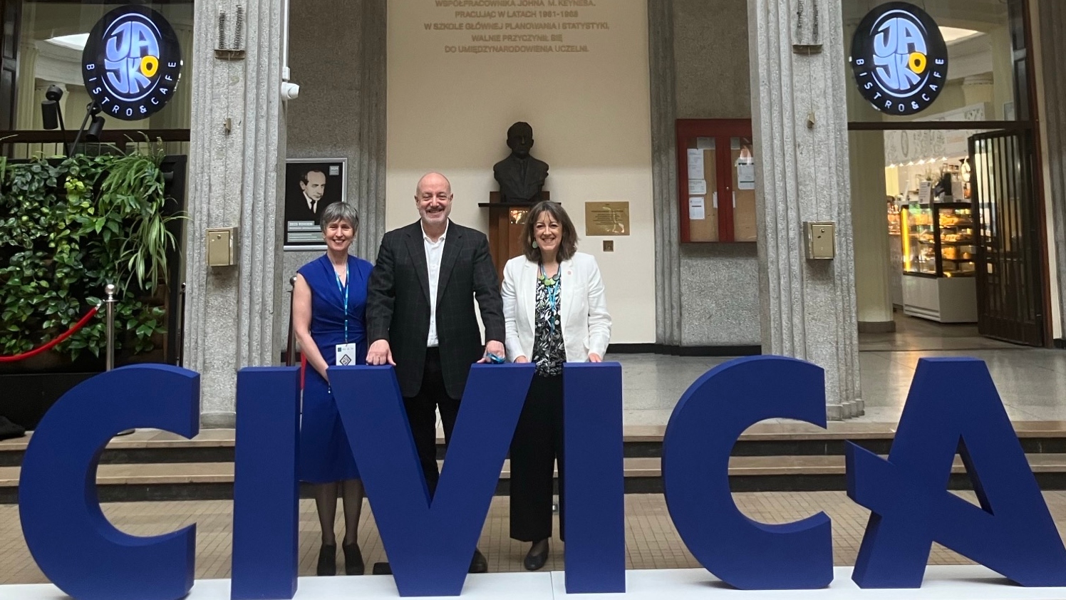 Larry Kramer, Emma McCoy and Susana Mourato posing behind large “CIVICA” letters inside a university building representing LSE at the CIVICA Presidents' Committee Meeting.