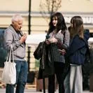 Three people standing outdoors; one eating an ice cream, two using phones.
