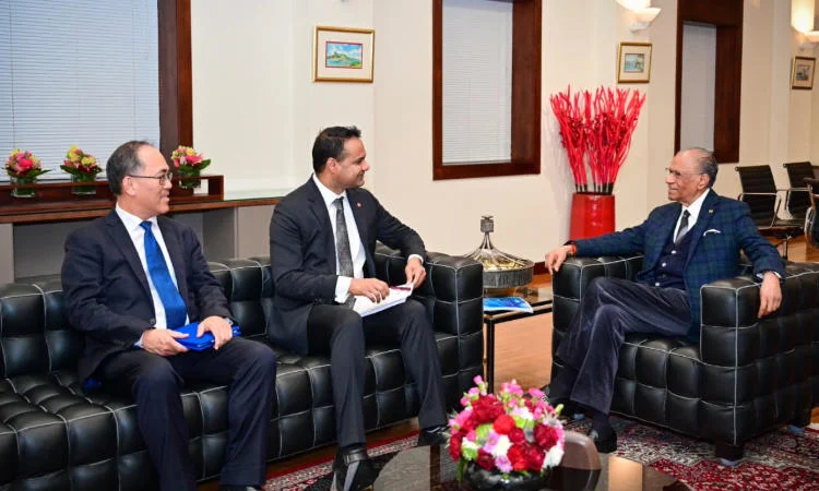 Three men in suits sat smiling and talking.