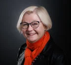 Headshot of Janet Foster. She is smiling and wearing a red scarf.