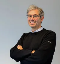 headshot of man smiling at the camera with his arms folded