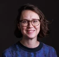 Haley McAvay headshot - she is smiling and wearing a blue jumper.