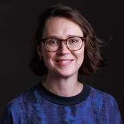 Haley McAvay headshot - she is smiling and wearing a blue jumper.