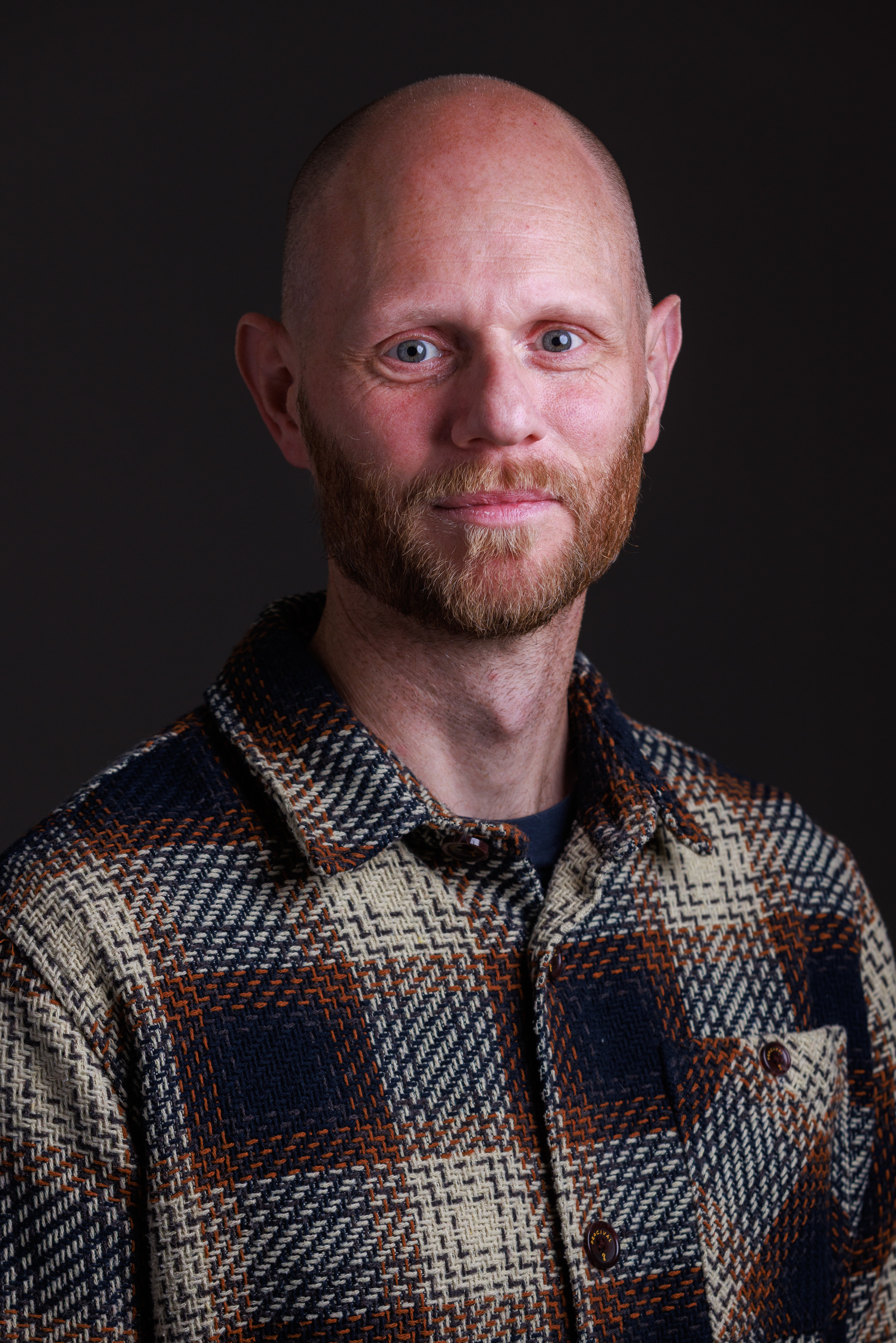 Professor Aaron Reeves headshot, he is smiling against a black backdrop.