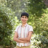 Sidra Kamran smiles at the camera with her arms folded