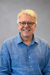 Headshot of Stephan Chambers in a blue shirt against a grey background