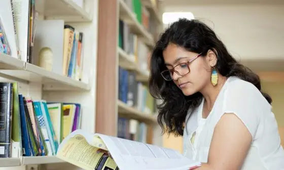 Global-Programmes-student-in-library-reading-through-documents