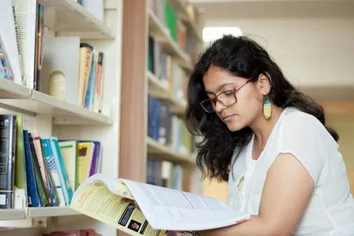 Global-Programmes-student-in-library-reading-through-documents