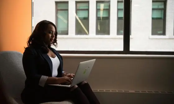Global-Programmes-young-businesswoman-sat-alone-by-window-on-laptop