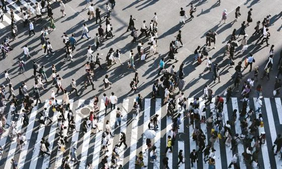 Aerial view of a crowded pedestrian crossing in a city, with people walking in multiple directions.