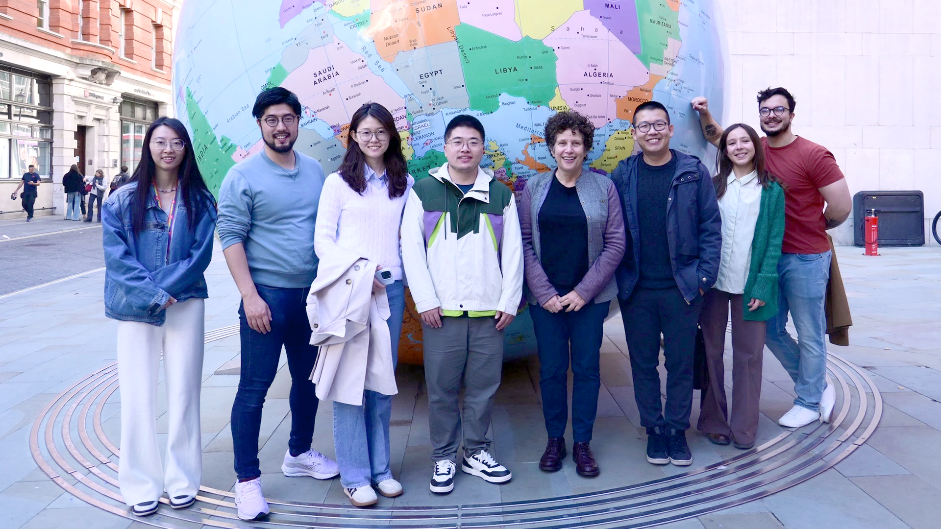 The Psychometrics Lab team standing in front of the globe on the LSE campus