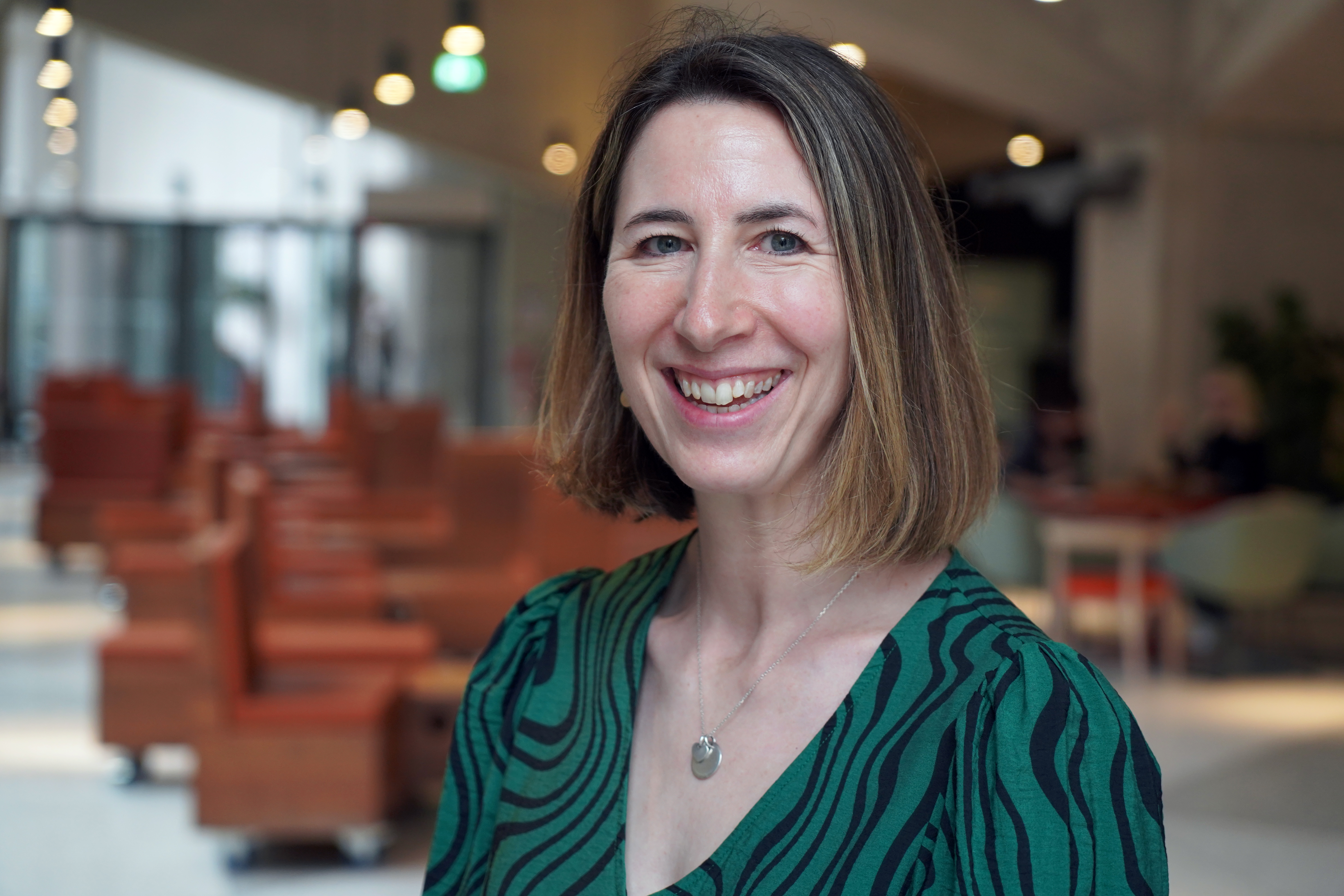 Rachel is wearing a green blouse and facing the camera at a slight angle. She is smiling.