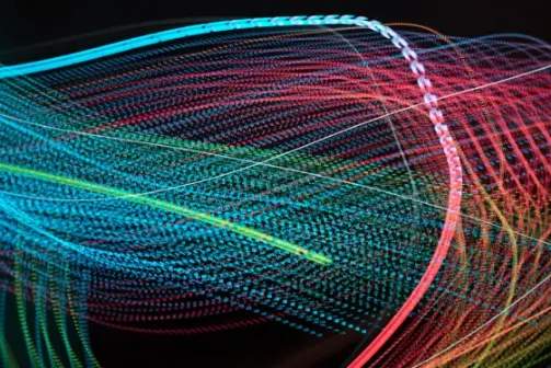 Abstract image featuring intertwined strands of vibrant colours, including blue, red, and yellow, against a dark background.