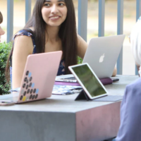 A group of female students with laptops sitting around a desk 