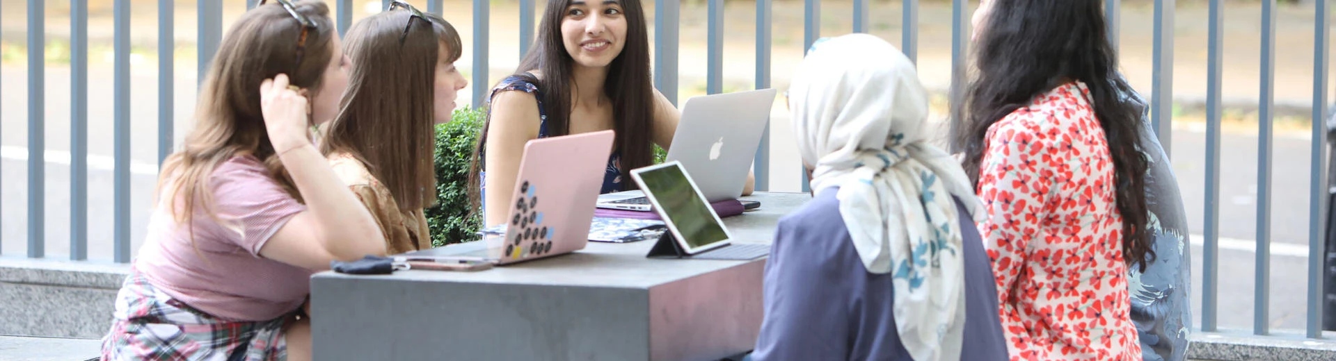 LSE research student group sitting on a terrace with laptops