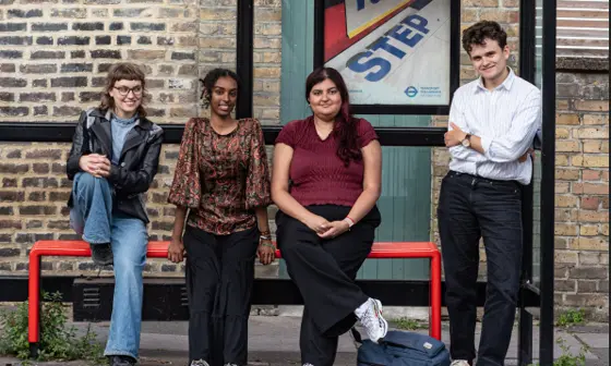 Four young people sitting and standing at a bus stop