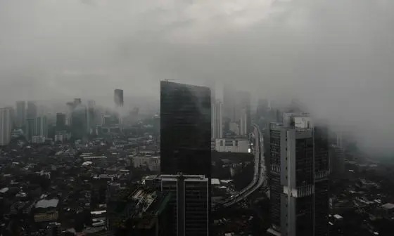 A bird-eye view of tall buildings in Jakarta shrouded in dark clouds.
