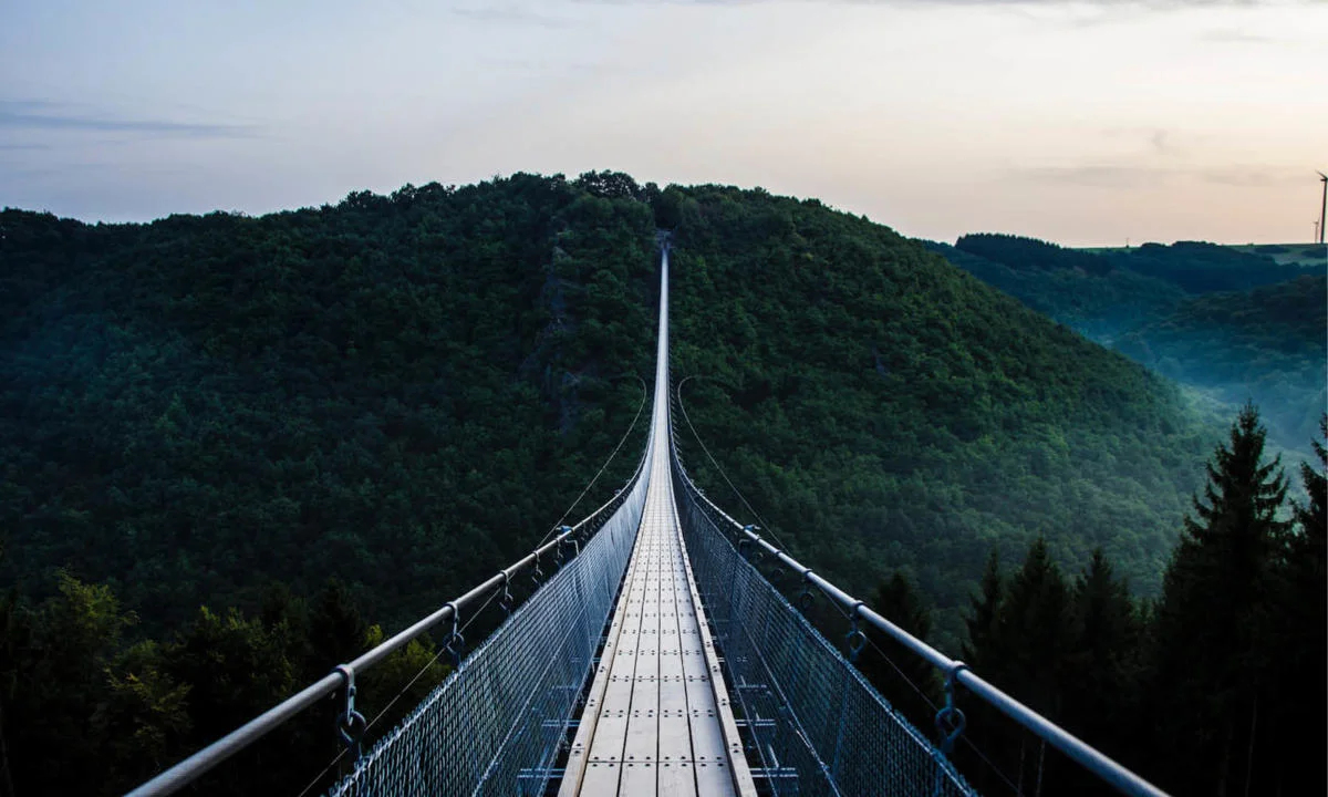 Wooden bridge across mountains covered by trees by Jonathan Klok, Unsplash