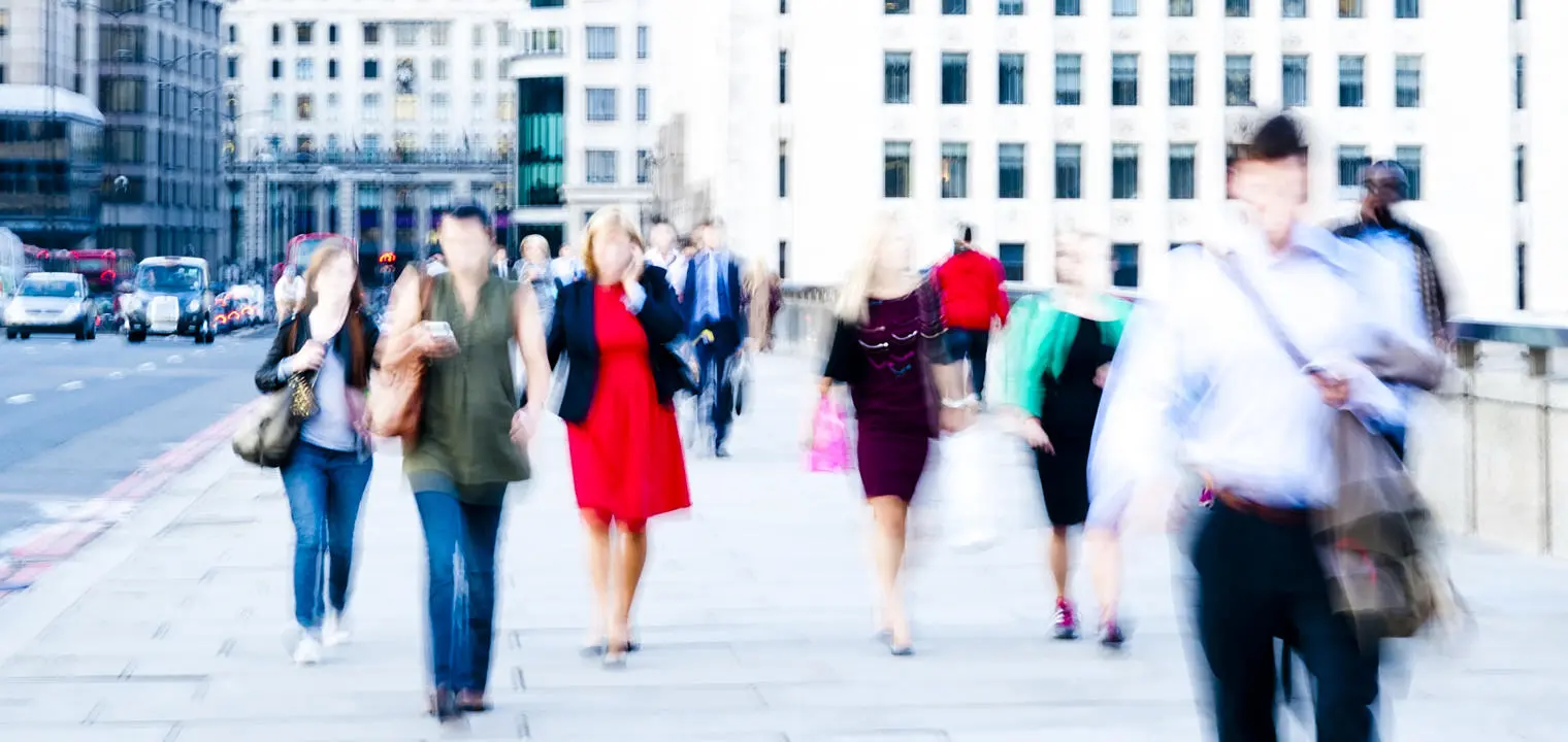 A blurred image of commuters walking in a city.