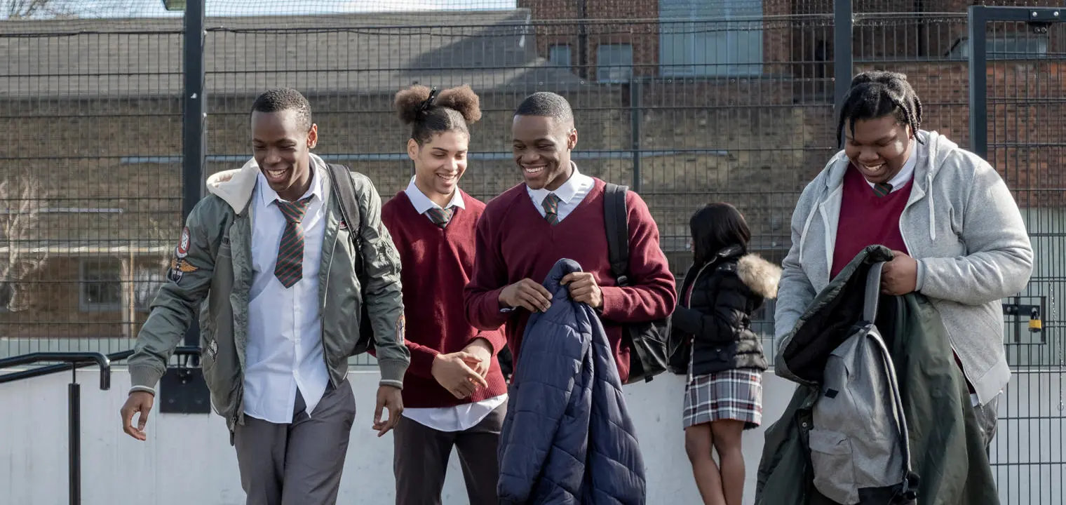Young men in school uniform walking and smiling.