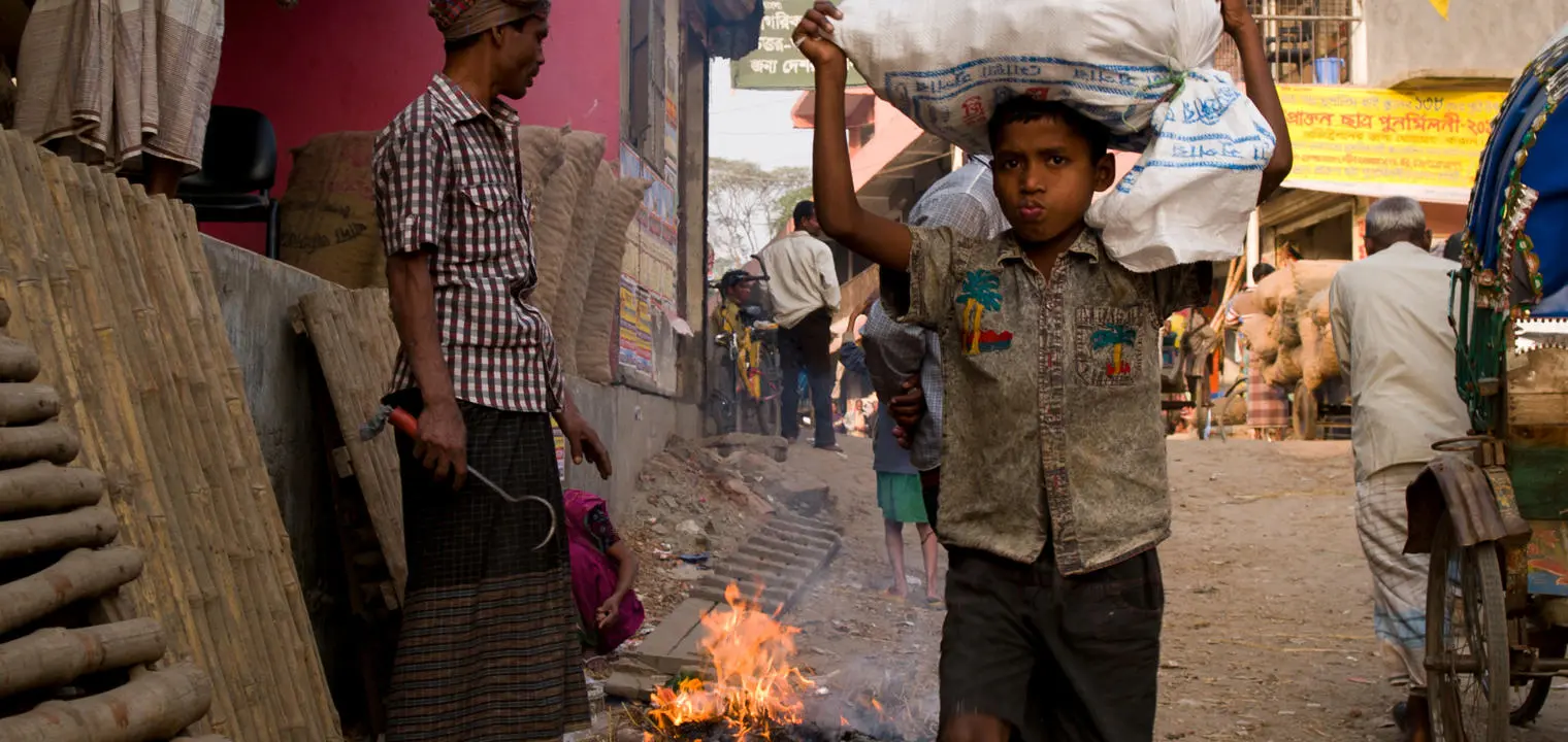 A boy carrying a bag on his head.
