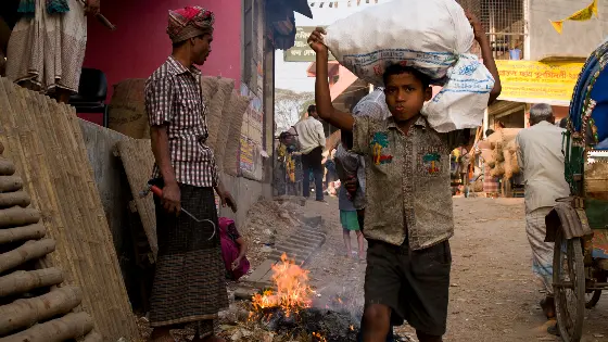 A boy carrying a bag on his head.