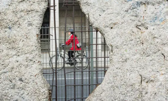 woman cycling seen through the Berlin wall