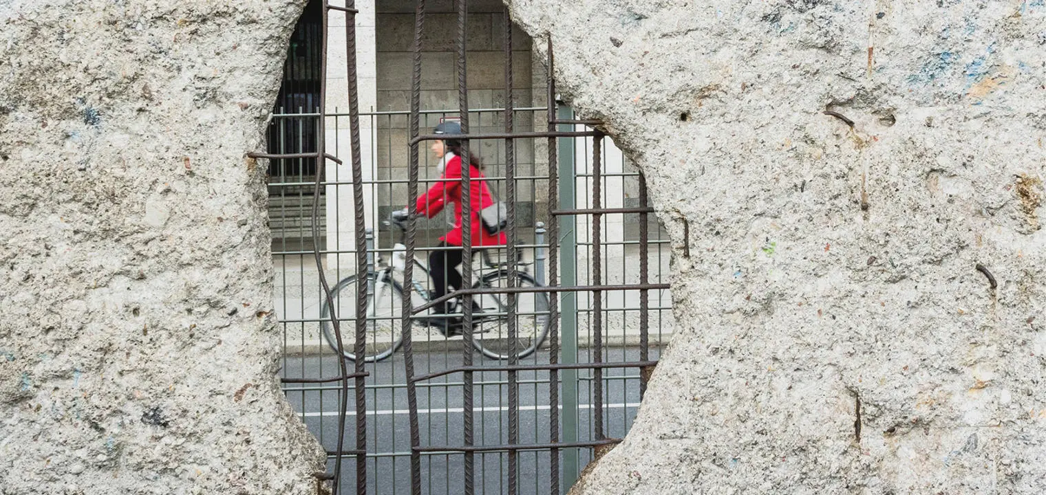woman cycling seen through the Berlin wall