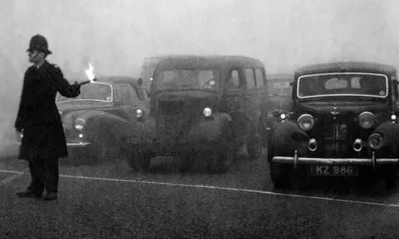Policeman guides traffic with flare in London's Great Smog, 1952