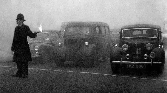 Policeman guides traffic with flare in London's Great Smog, 1952