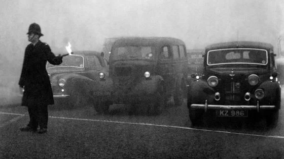 Policeman guides traffic with flare in London's Great Smog, 1952