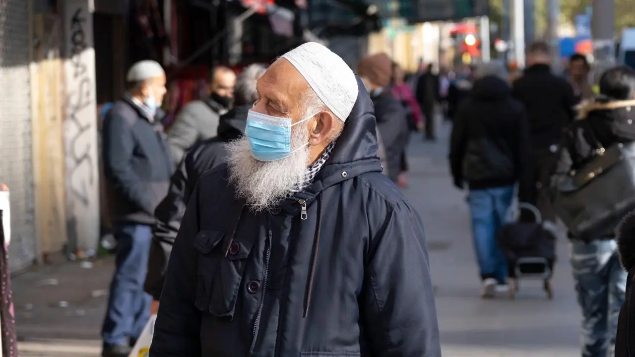 A man in a high street wearing a face mask