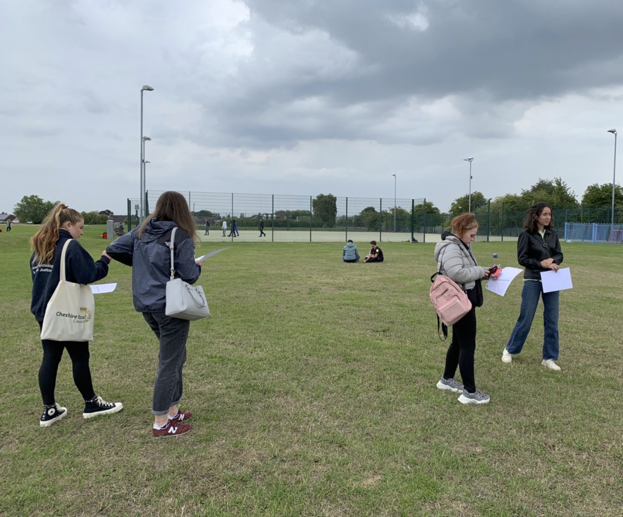 Three researchers-in-residence visiting a typical neighbourhood park in Crewe with basketball and football court and playground. 