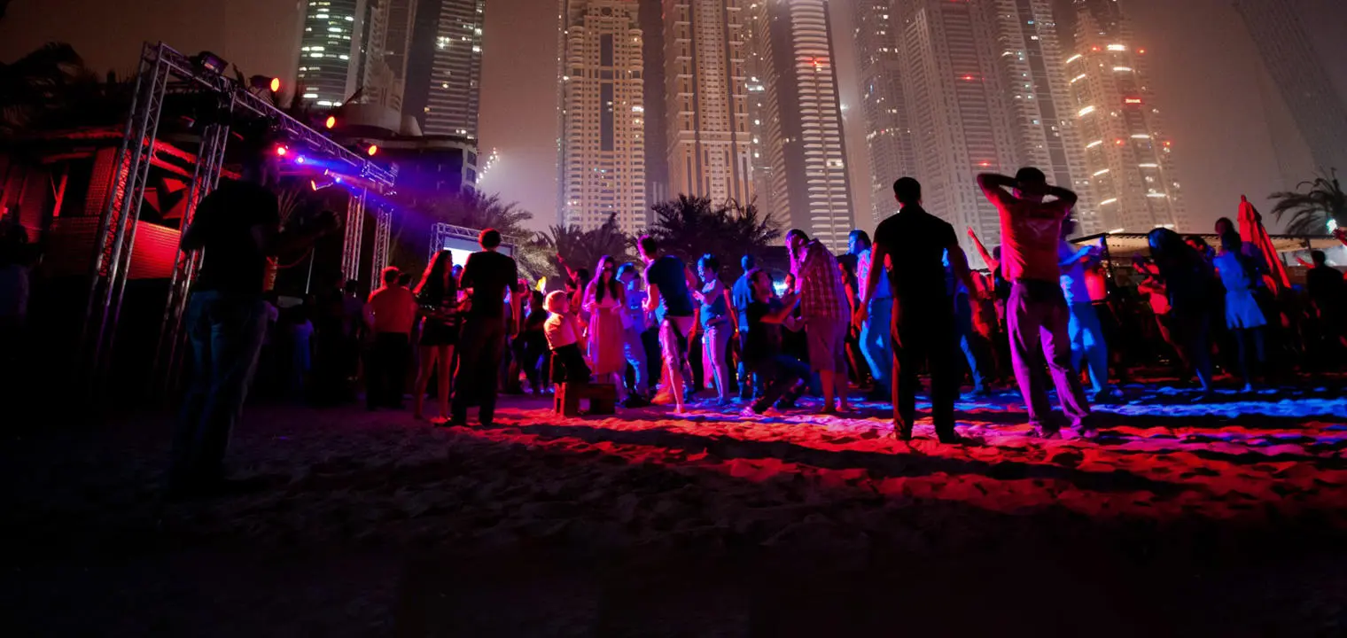 People dancing at a nightclub under Dubai skyline