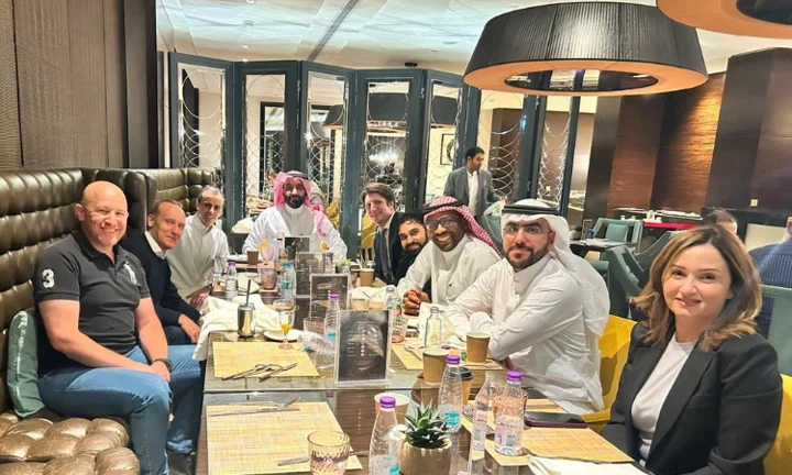 Alumni in Riyadh around a table.