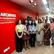 Group of people standing in a hallway next to a red wall with “Archives of Contemporary India” signage