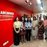 Group of people standing in a hallway next to a red wall with “Archives of Contemporary India” signage