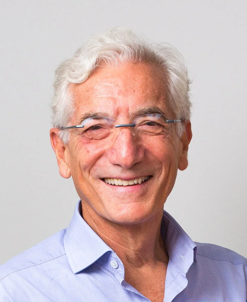Headshot of a man wearing a blue shirt against a grey background