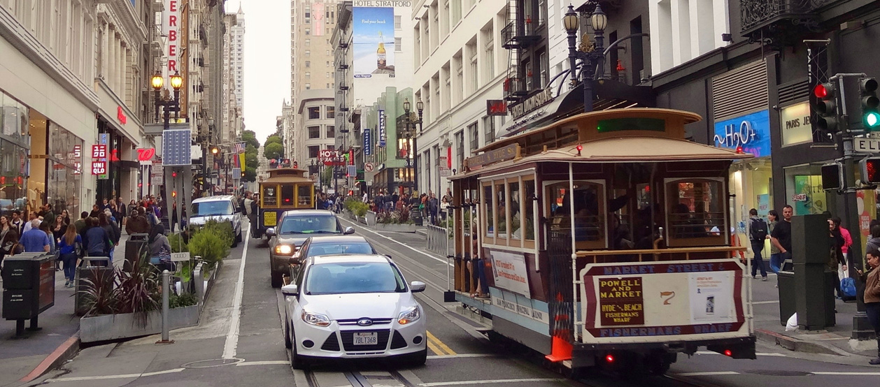 A busy San Francisco street with trams and cars.