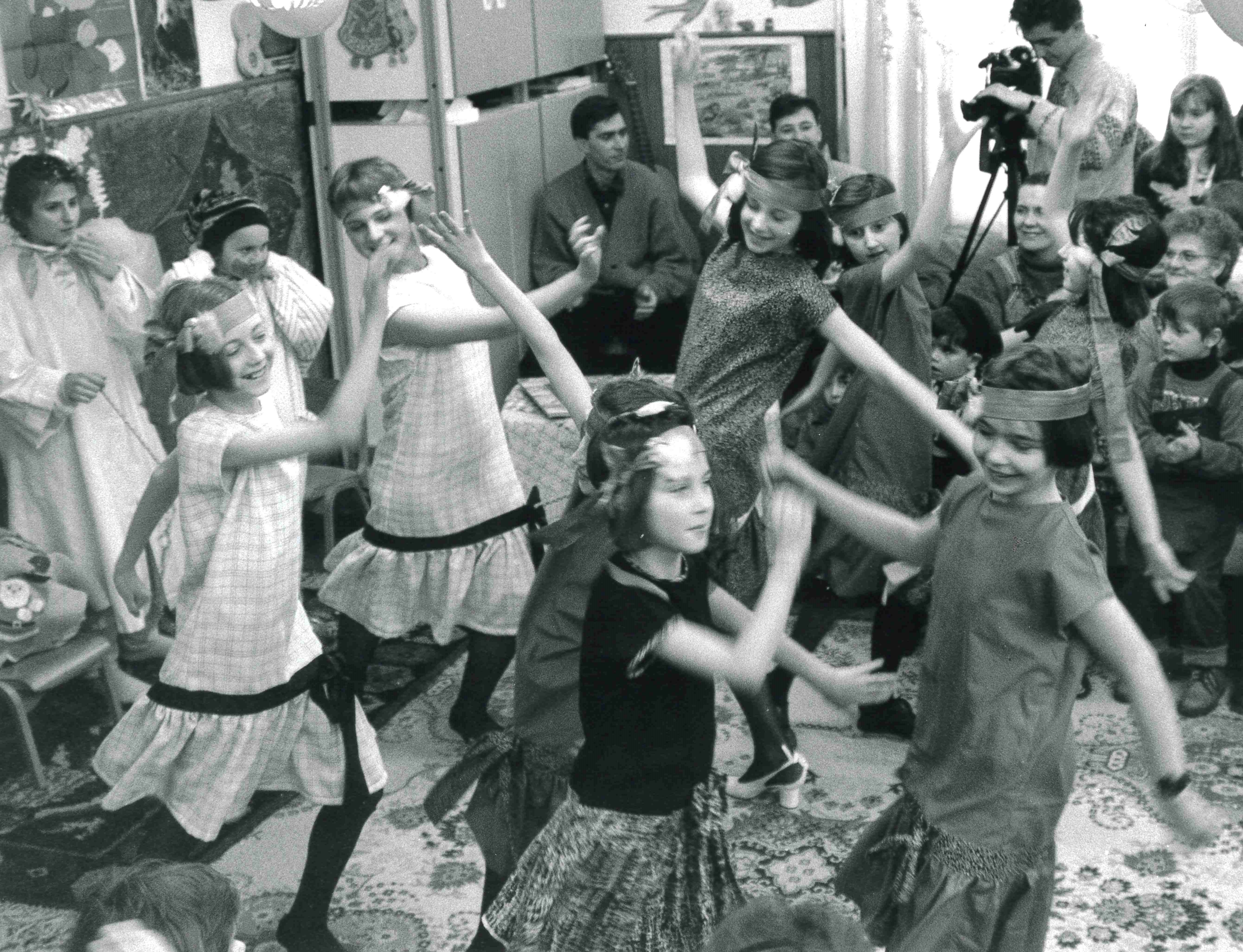 A group of girls dancing around a room for an audience.